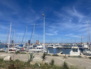 Ein Yachthafen mit mehreren vor Anker liegenden Booten, bewölktem Himmel und einer Straßenlaterne.