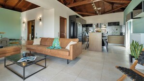 Ein modernes Wohnzimmer mit einer Couch, einem Couchtisch und einer Küche im Hintergrund.