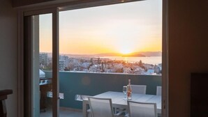 Ein Balkon mit Tisch und Stühlen mit Blick auf eine Stadtlandschaft bei Sonnenuntergang.
