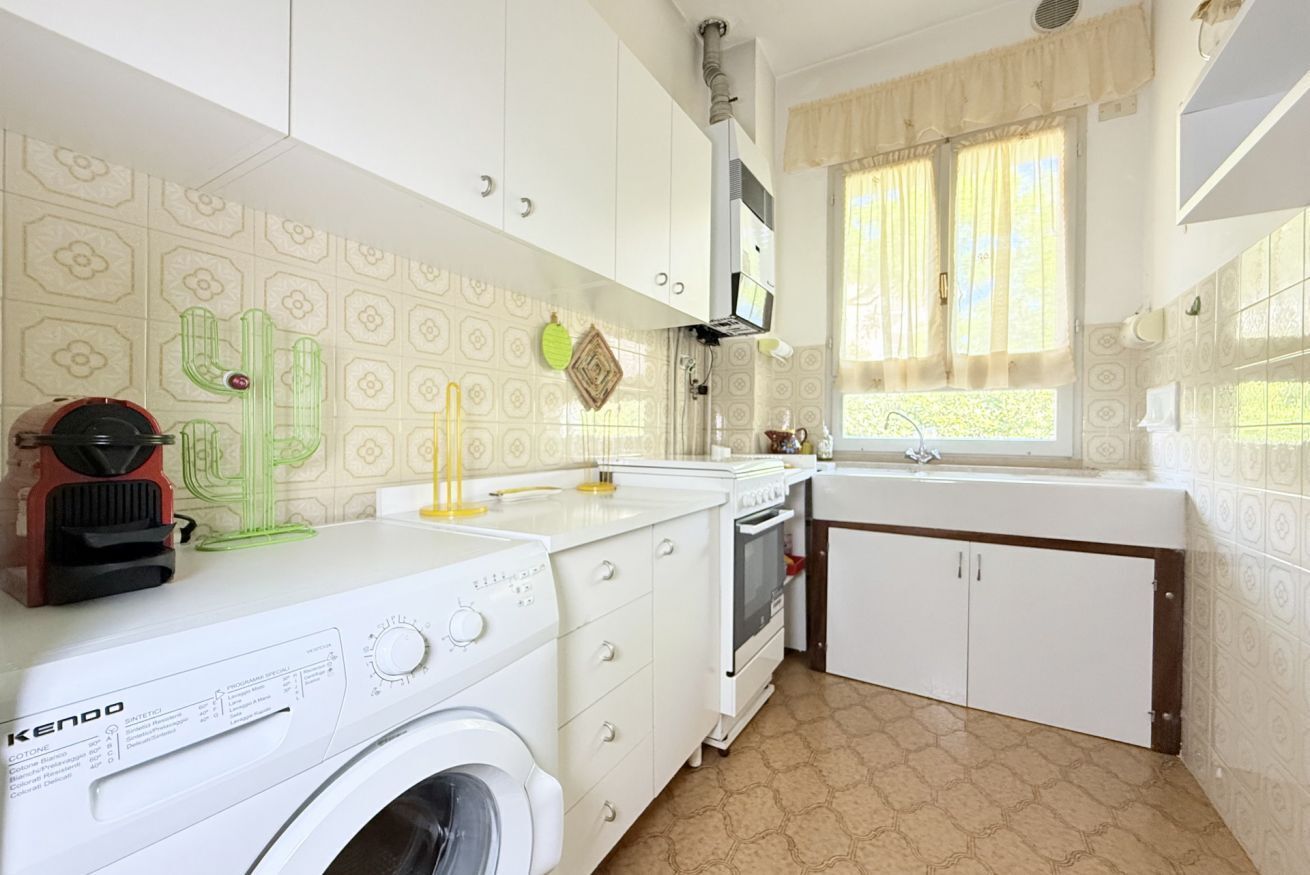 A compact kitchen with a washing machine, a stove, and a sink.
