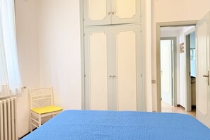 A bedroom with a bed, a chair, a wardrobe, and an open door leading to another room. - M436 - Marcelli, three-room apartment with garden, 150 meters from the sea (Marcelli)