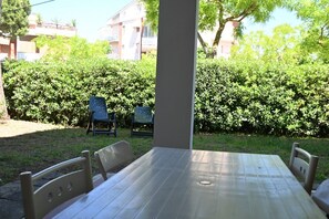 A patio with a table and chairs, surrounded by a hedge and buildings in the background. - M436 - Marcelli, three-room apartment with garden, 150 meters from the sea (Marcelli)