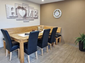 Ein Essbereich mit einem Holztisch, schwarzen Polsterstühlen, einer Uhr und einem Schild mit der Aufschrift 'HOME' an der Wand.