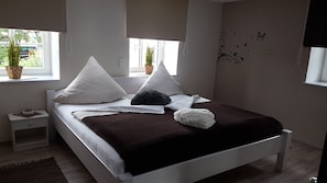 A bedroom with a bed, pillows, a nightstand, a bedside table, a window with a view, and a wall with butterfly decals. - Eifel Dream Country House with Private Outdoor Hot Tub and Sauna (Plütscheid)