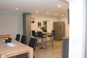 A modern dining area with a wooden table, black chairs, and a vase of flowers. - Eifel Dream Schneifelhaus with Private Outdoor Hot Tub and Barrel Sauna (Roth bei Prüm)
