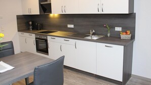 Ett modernt kök med vita skåp, en diskho i rostfritt stål och en inbyggd ugn.