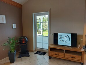 A room with a television on a wooden stand, a potted plant, and a door leading outside. - Eifel Dream Wildeiche with Private Outdoor Hot Tub and Sauna (Fleringen)