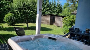 Ein Whirlpool mit herzförmiger Dekoration an einer Säule, umgeben von einem Rasen und Bäumen.