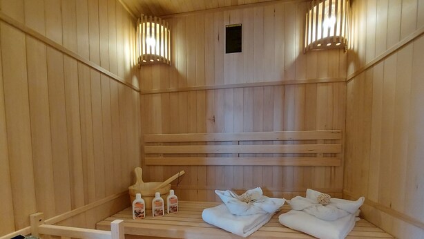 Eine Holzsauna mit Bänken, Wasserflaschen und Handtüchern.