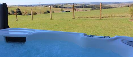 Een hottub met uitzicht op een grasveld en een omheining.