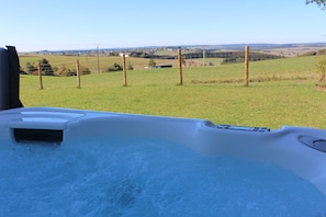 Ein Whirlpool mit Blick auf ein Wiesenfeld und einen Zaun.
