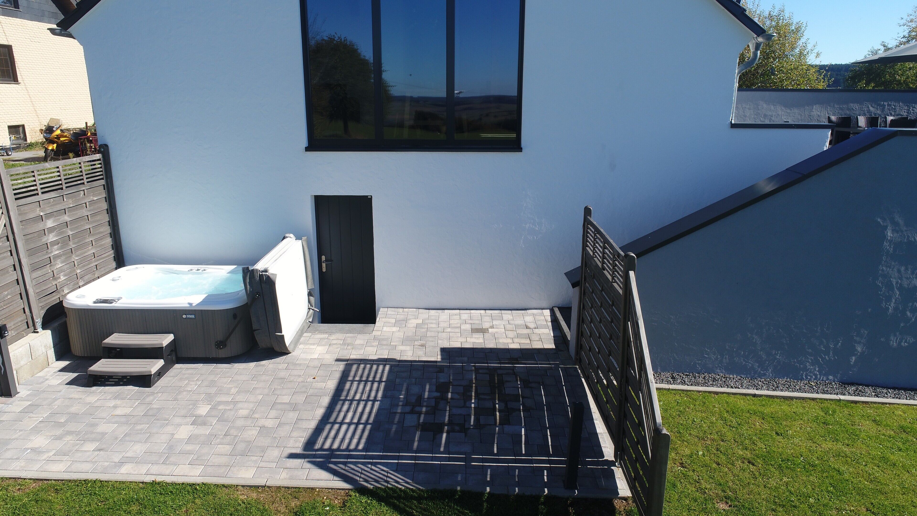 Ein modernes Haus mit Whirlpool, einer Tür und einem Fenster.