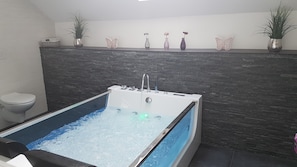 Ein modernes Badezimmer mit einer freistehenden Badewanne, einer Toilette und dekorativen Vasen auf einem Regal.