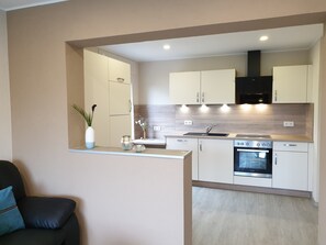 Een moderne keuken met witte kasten, een inbouwoven en een aanrecht met een vaas en decoratieve objecten.