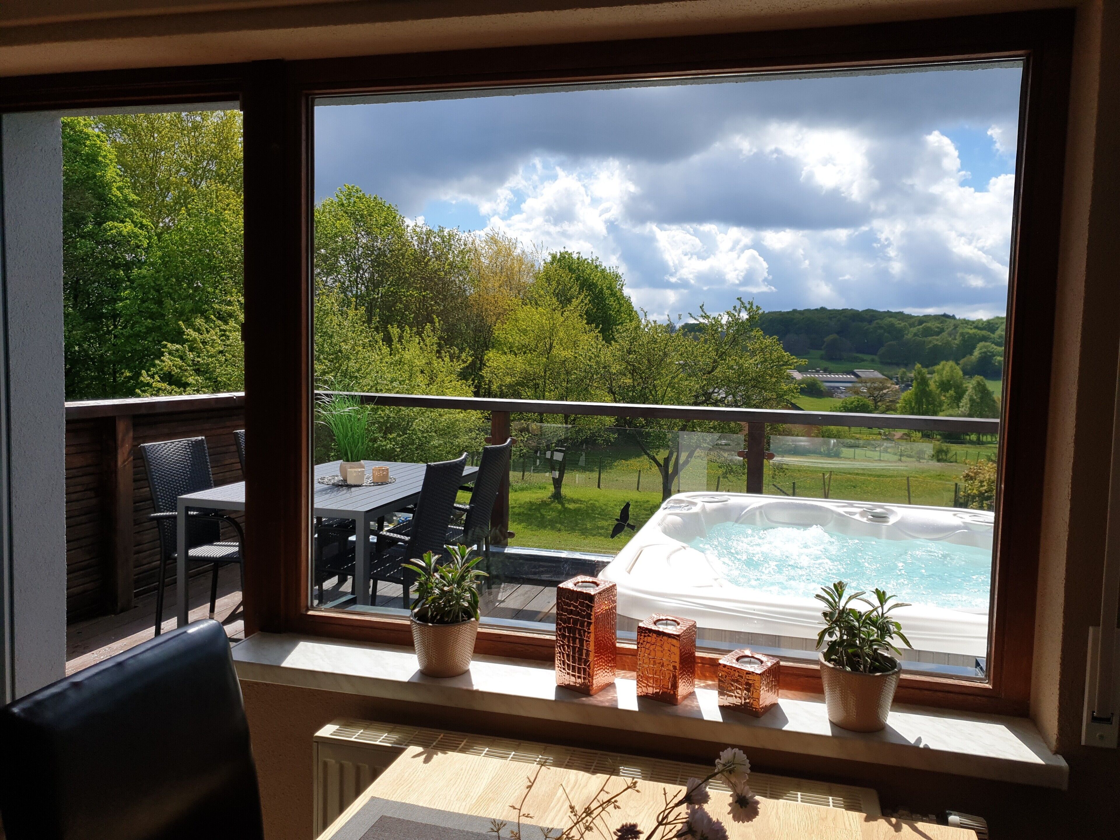 A balcony with a table, chairs, potted plants, and a hot tub.. Eifel Dream Kupferbach with Private Outdoor Hot Tub and Sauna