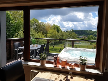 A balcony with a table, chairs, potted plants, and a hot tub.. Eifel Dream Kupferbach with Private Outdoor Hot Tub and Sauna