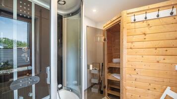 Ein modernes Badezimmer mit Duschkabine aus Glas, einem Holzwaschtisch und einer integrierten Regaleinheit.