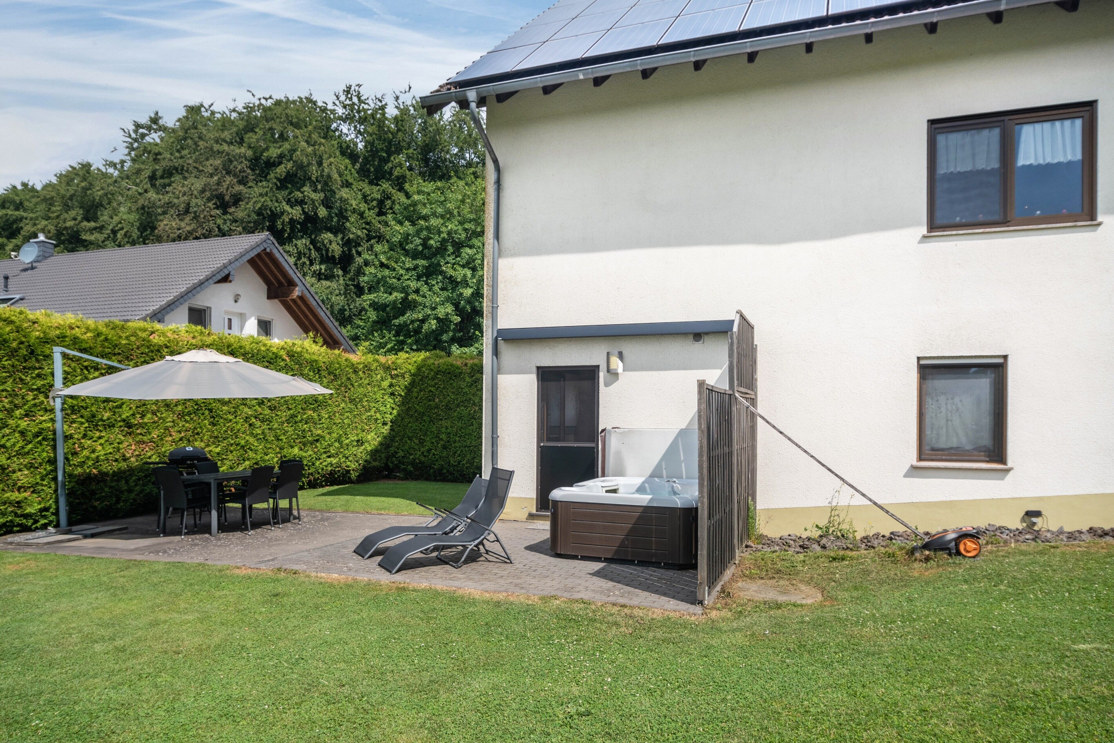 Une maison dotée d’un patio, d’un espace salon extérieur, d’un jacuzzi et d’un panneau solaire.