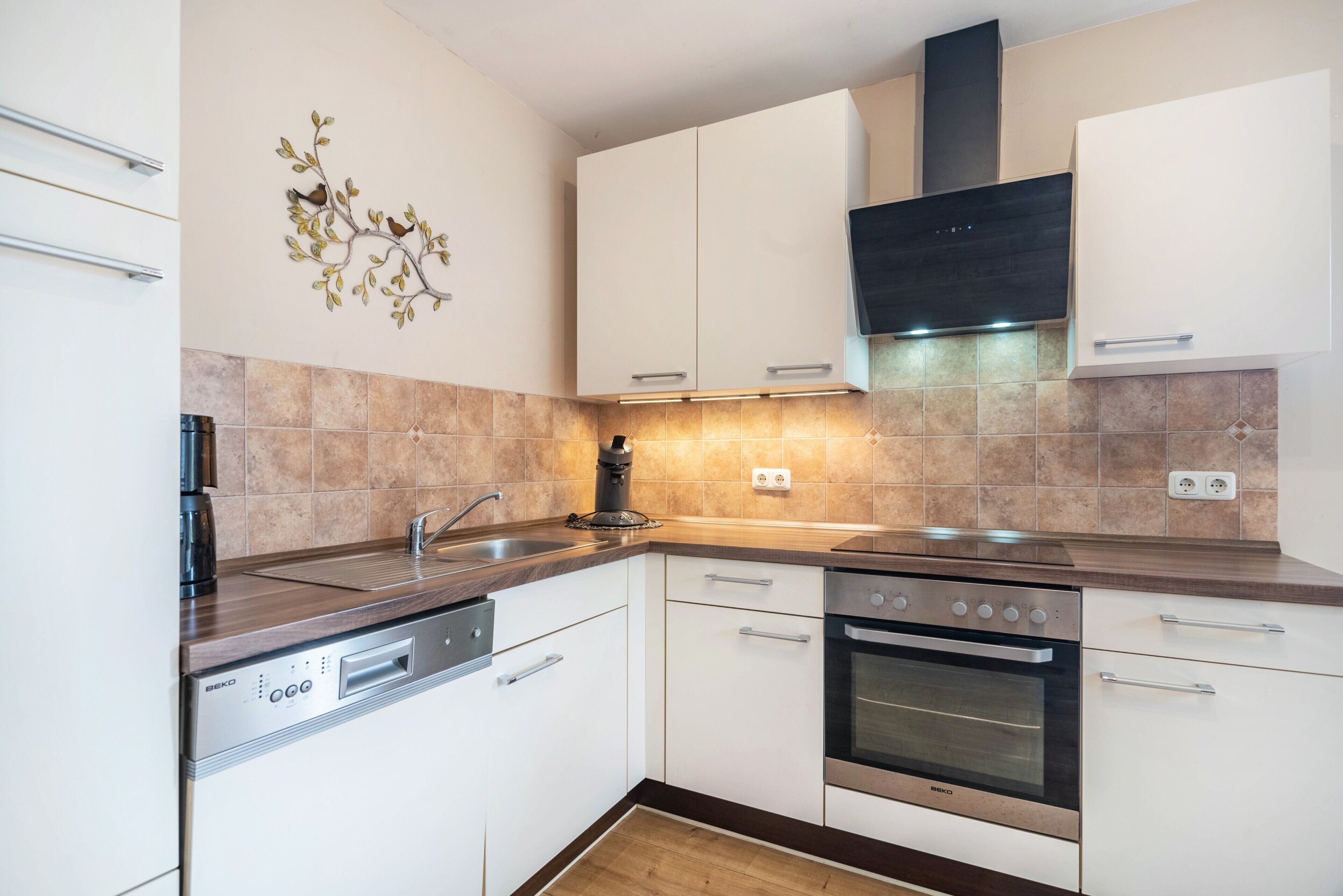 A modern kitchen with white cabinets, a built-in oven, and a dishwasher.