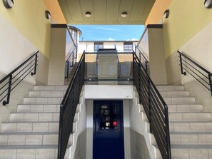 Eine Treppe mit schwarzen Geländern, einem Glasgeländer und Blick auf Gebäude im Hintergrund.