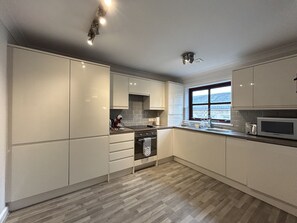 Eine moderne Küche mit großem Fenster, eingebauten Geräten und einem Fischgrätparkett.