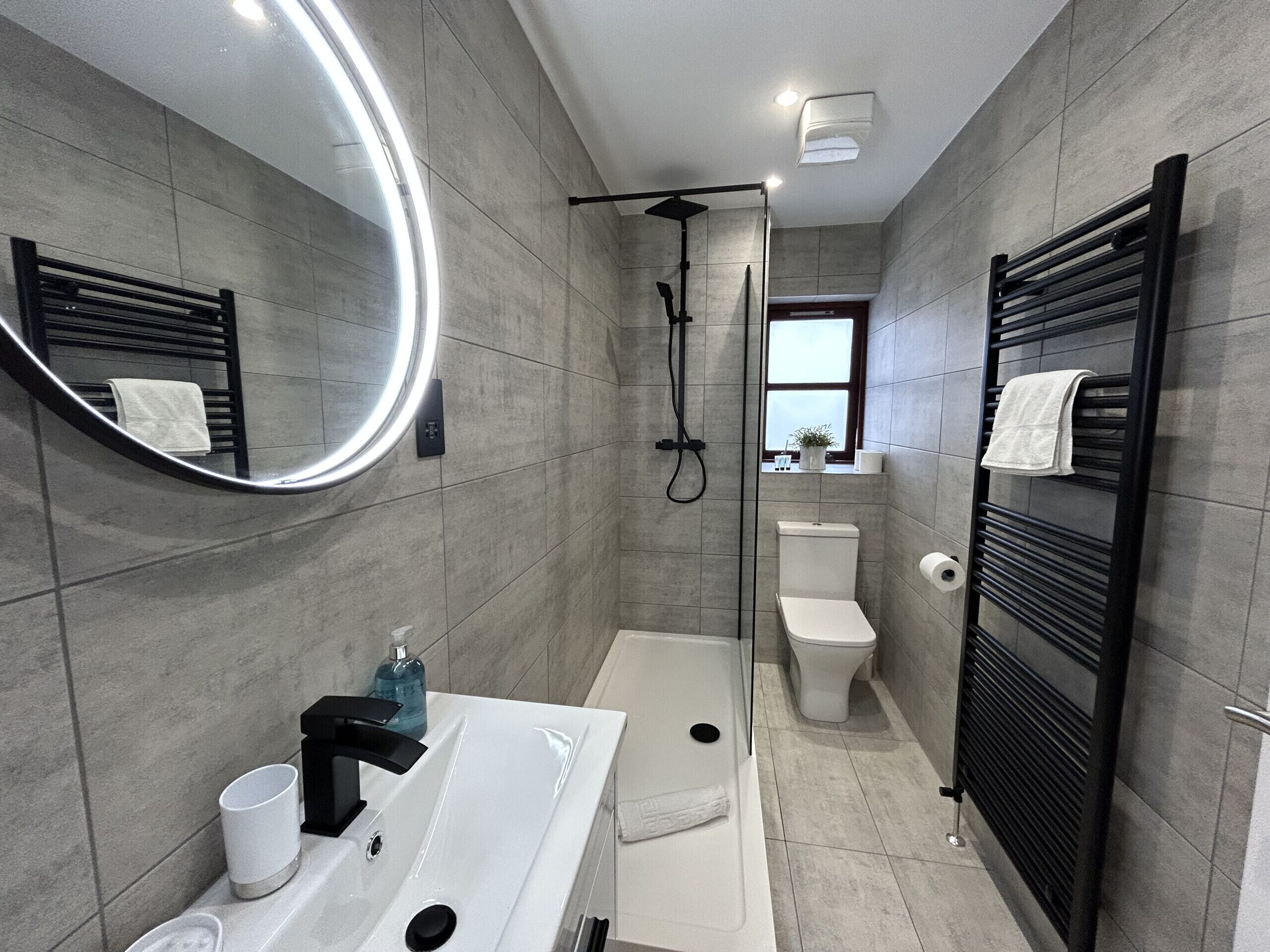 A modern bathroom with a shower, toilet, and sink.