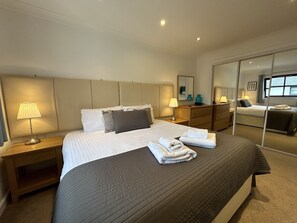 Ein Hotelzimmer mit einem großen Bett, Nachttischen, einem Schminktisch und einem Fenster.
