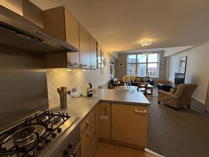 Eine moderne Küche mit Gaskochfeld, Holzschränken und einem Essbereich mit Sofa und Couchtisch.