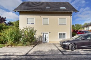 Een tweelaags huis met een verharde oprit en een geparkeerde auto.