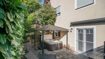 En patio med jacuzzi, udendørs møbler og en overdækket siddeplads.