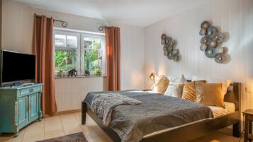 Ein Schlafzimmer mit einem Bett, einem Fernseher, einem Schminktisch und einem Fenster mit Vorhängen.