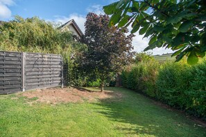 Een omheinde achtertuin met een gazon, een boom en een houten schutting.