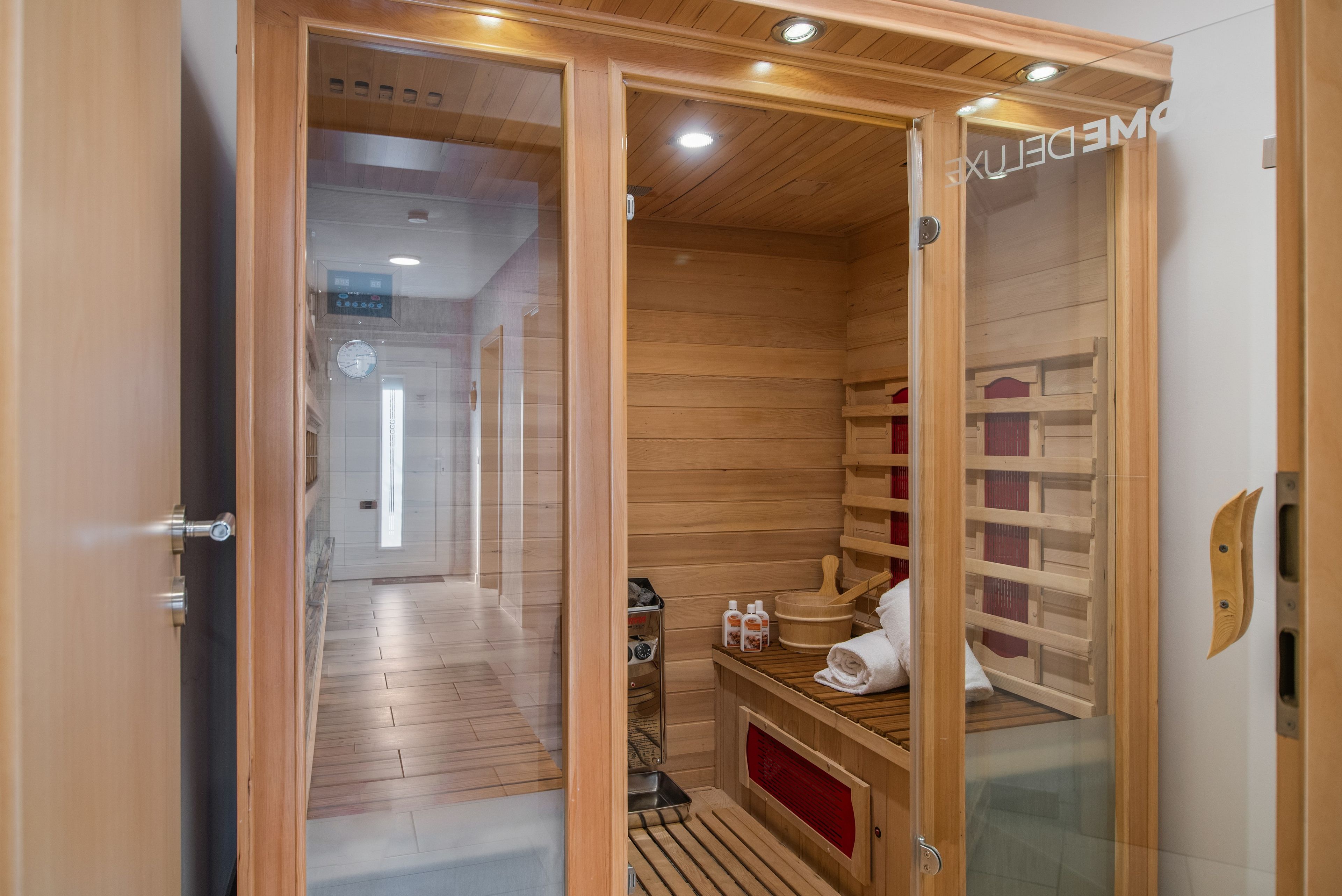 A sauna room with wooden walls, a bench, a bench seat, a towel, and a wooden bucket.