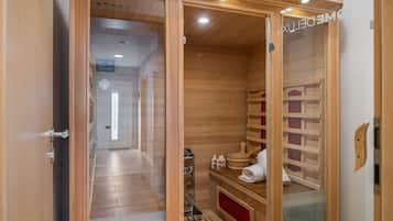 A sauna room with wooden walls, a bench, a bench seat, a towel, and a wooden bucket.