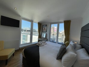 Ein Hotelzimmer mit Bett, Fernseher, Fenster mit Blick auf Gebäude und Stuhl.