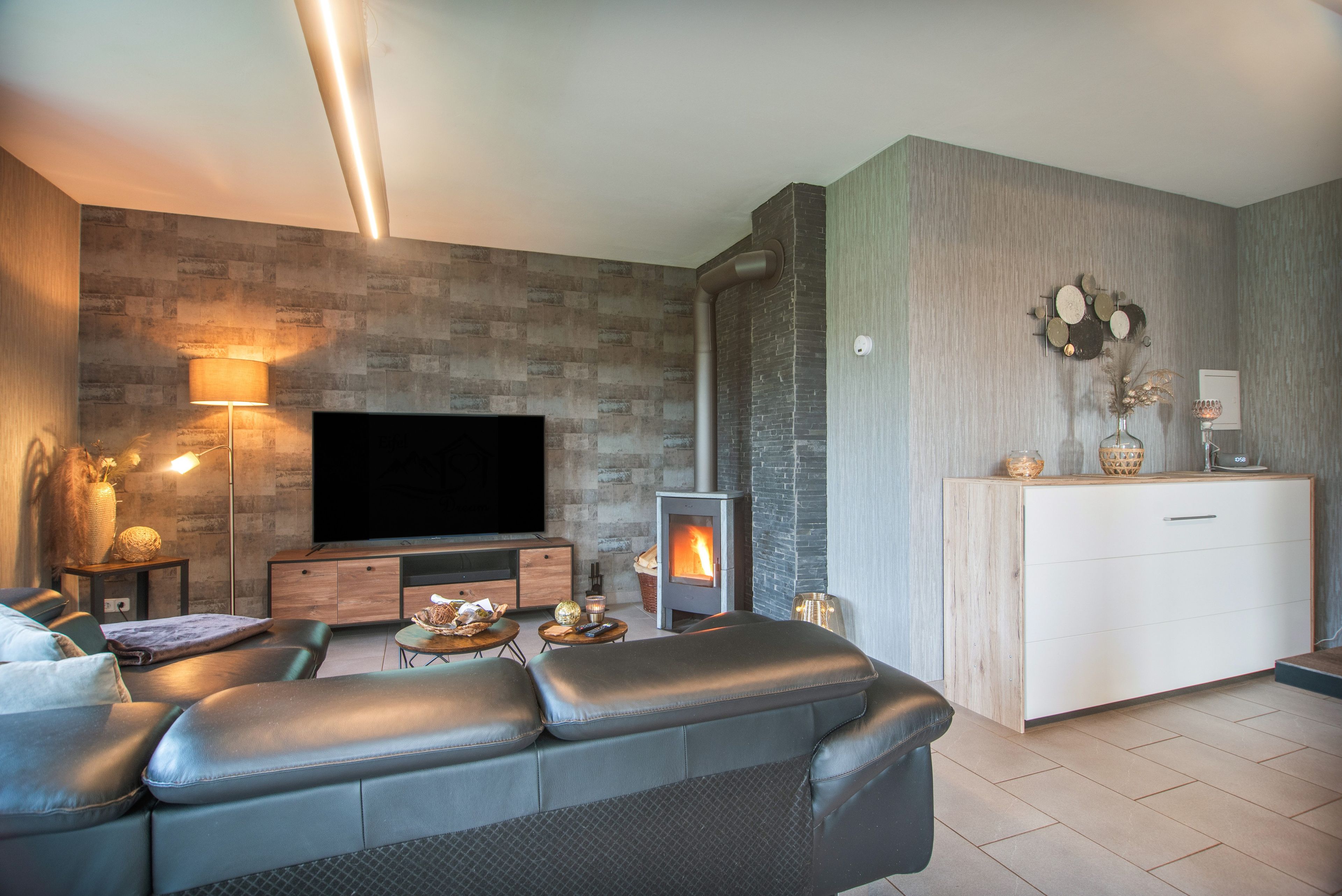 A modern living room with a flat-screen TV, a fireplace, a sofa, and a small side table.