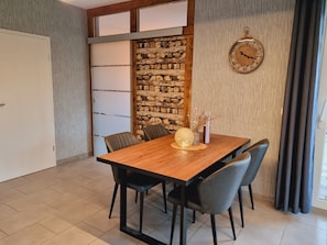 Un coin repas comprenant une table en bois, quatre chaises, une sphère décorative et une horloge murale.