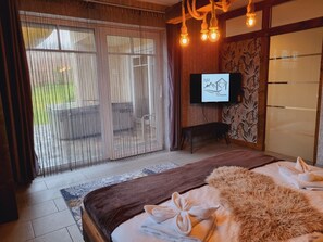 Hotellihuone, jossa on sänky, televisio, penkki ja näkymä ulos.