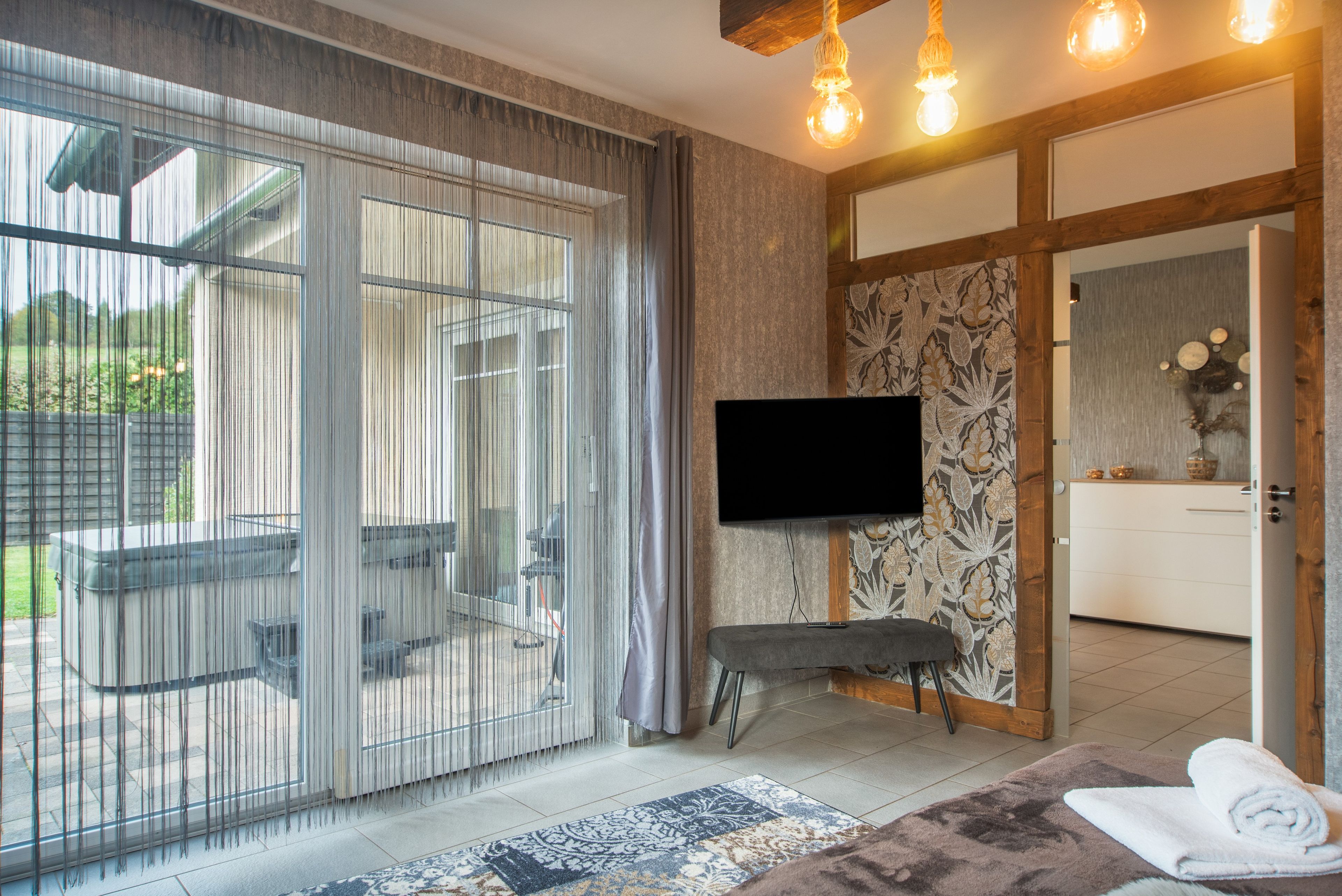 A modern bathroom with a large mirror, a flat-screen TV, and a bench.