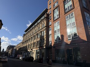 A multi-story building with large windows and a storefront labeled 'Tinderbox.' - Ingram One Bedroom Apartment (Glasgow)