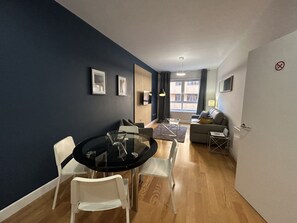 Ein modernes Wohnzimmer mit Esstisch, Stühlen, einer Couch und einem Fernseher.