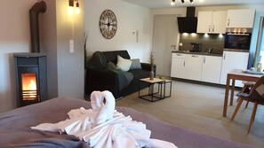 Una sala de estar moderna con chimenea, un sofá, una zona de comedor y una cocina al fondo.