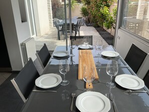 A dining table set for six with chairs, plates, wine glasses, and cutlery. - Villa with pool Between sea and nature (Lattes)