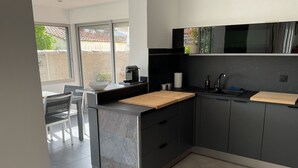 A modern kitchen with a large island, dark cabinetry, and a view of the outdoors. - Villa with pool Between sea and nature (Lattes)