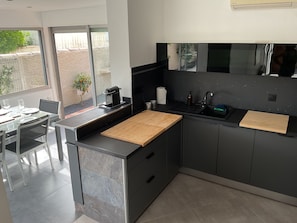 A modern kitchen with a large island, a built-in oven, and a sink. - Villa with pool Between sea and nature (Lattes)