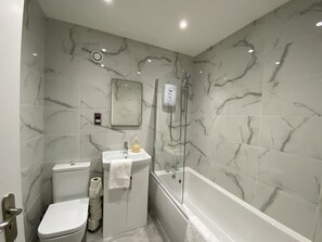 Ein Badezimmer mit Toilette, Waschbecken und Badewanne, alles mit Marmorwänden und modernem Design.
