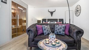 Ett modernt vardagsrum med en lädersoffa, ett soffbord med ljus, en väggdekoration i form av ett noshörningsskalle och en klocka.