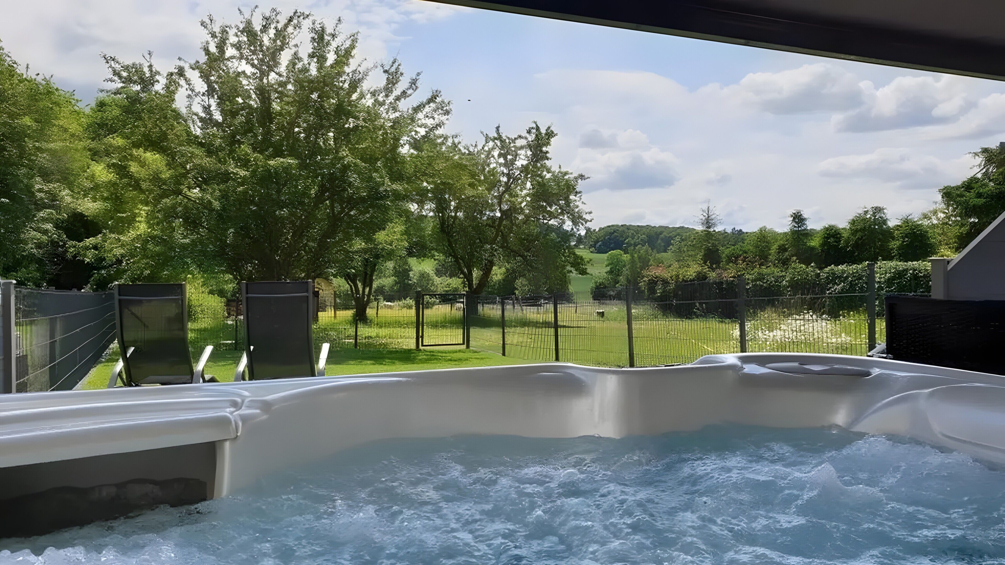 A hot tub with a view of a fenced garden and trees.. Eifel Dream Kalkmulde with Private Outdoor Hot Tub and Sauna