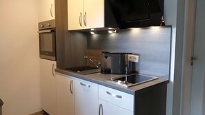 Une cuisine moderne équipée d’appareils électroménagers en acier inoxydable, d’un four encastré et d’une machine à café.