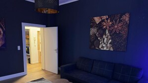 Un salón con decoración oscura, un sofá, una mesa de centro y un cuadro en la pared.